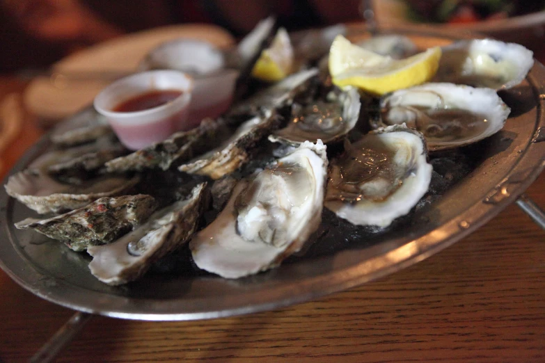 an aluminum dish full of oysters on a wooden table