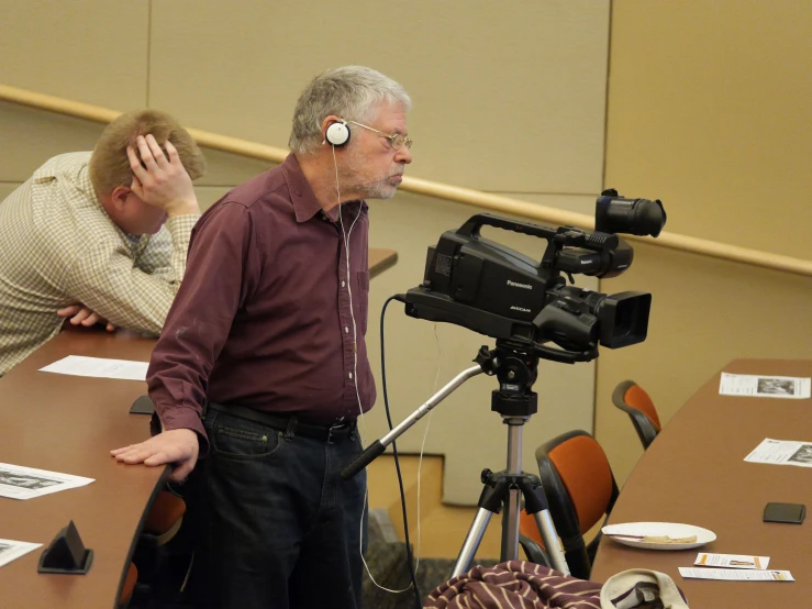 two men wearing headsets are talking to someone at the table