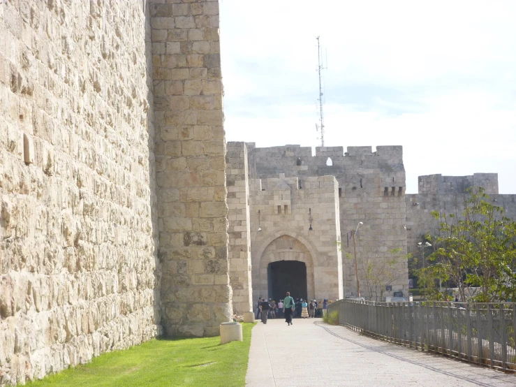 people walk along a stone path toward a gate