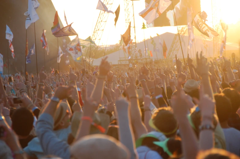 a crowd in a city holds their hands up for the sun