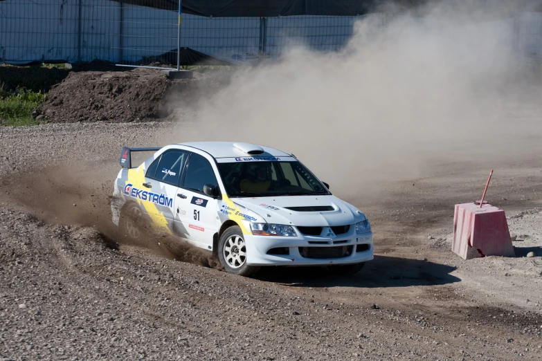 a white car driving on top of a dirt field