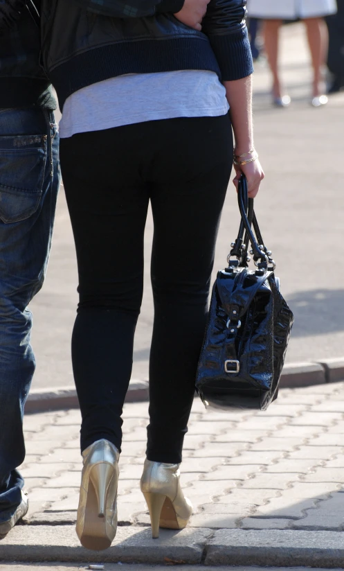 a couple walks down the sidewalk holding a purse