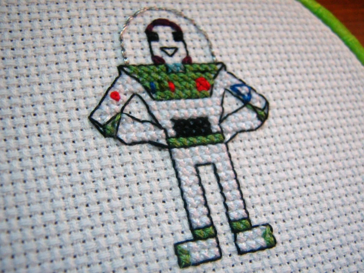 a cross stitch picture of a man in a space suit