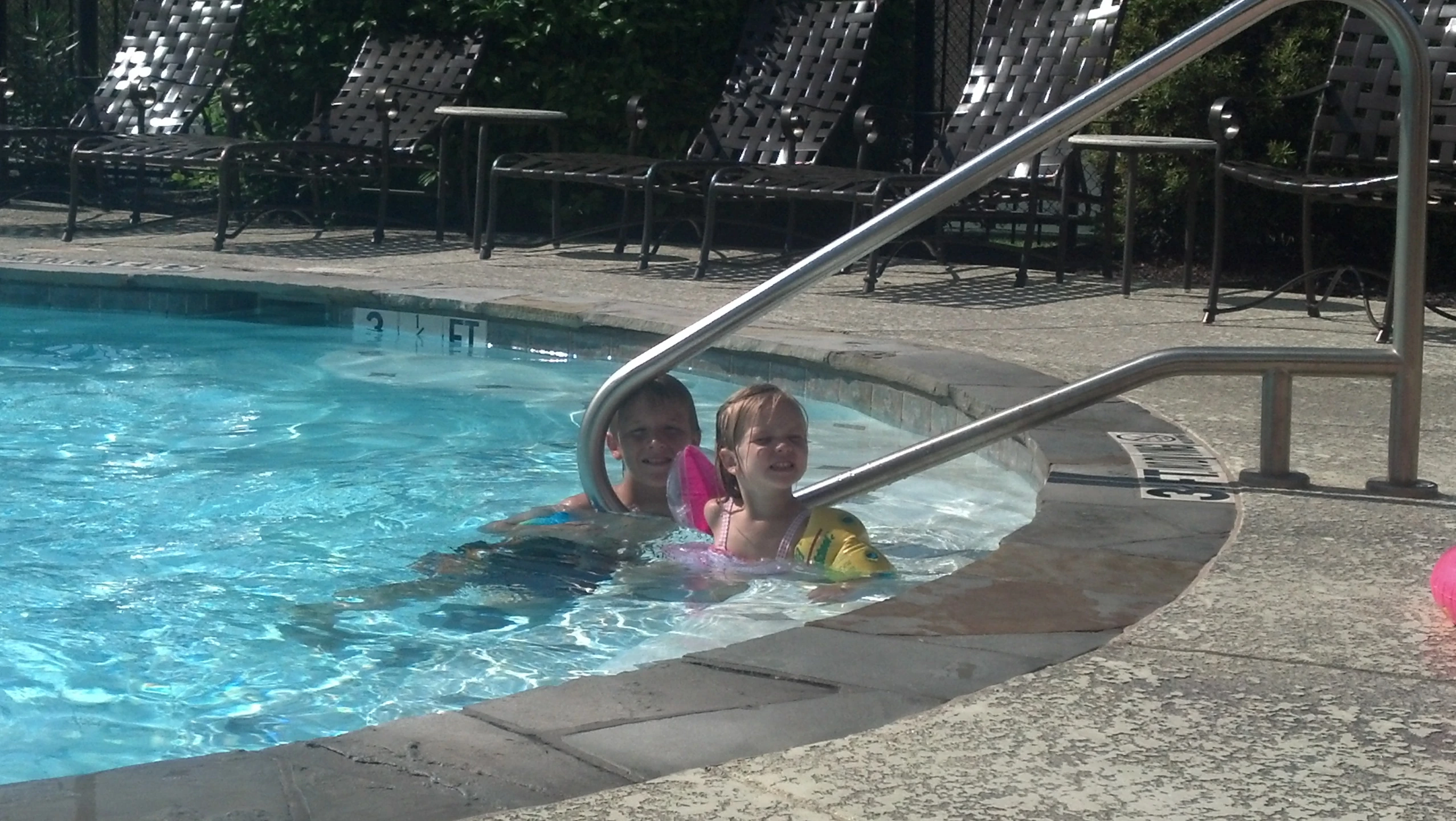 two girls are swimming in a pool on an island