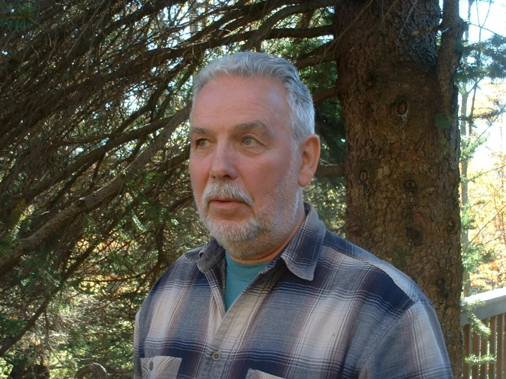 an older man wearing a shirt in the forest