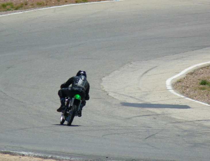 a man riding a green motorcycle on top of a curvy road