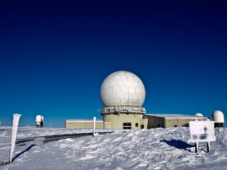 a white satellite dish on top of snow covered ground