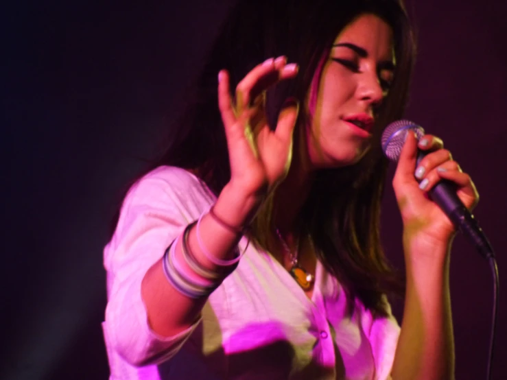 woman on stage singing into a microphone and lighting