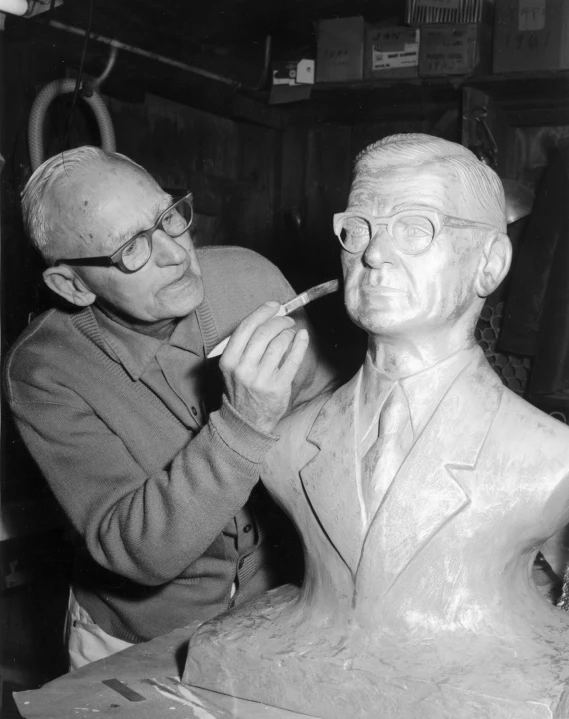 black and white pograph of a man brushing his teeth next to a sculpture