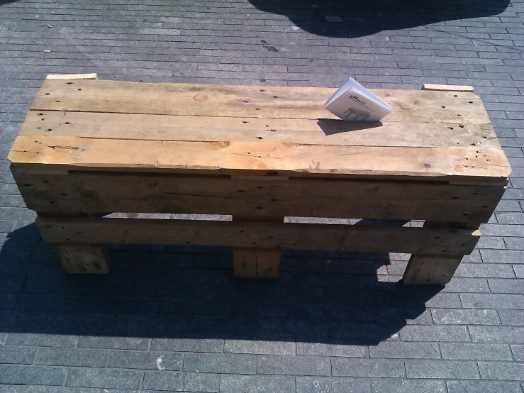 a wooden bench is sitting on the pavement