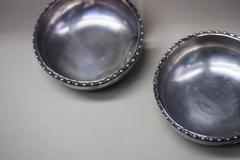 two small, silver bowls sitting on top of a table