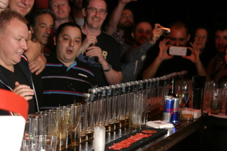 a large crowd watches a man standing in front of a bar