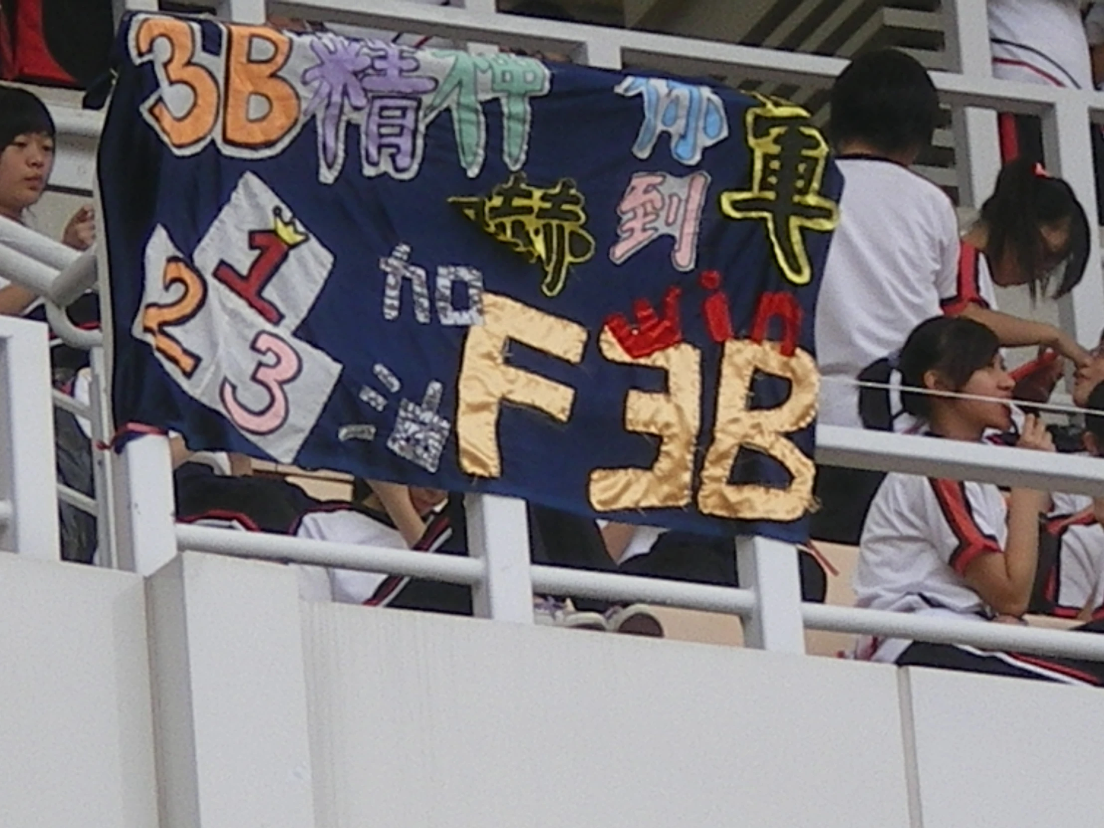 some fans are holding up an image on a stadium's fence