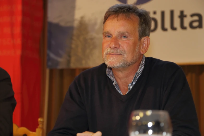 a man in black shirt sitting down and having a discussion