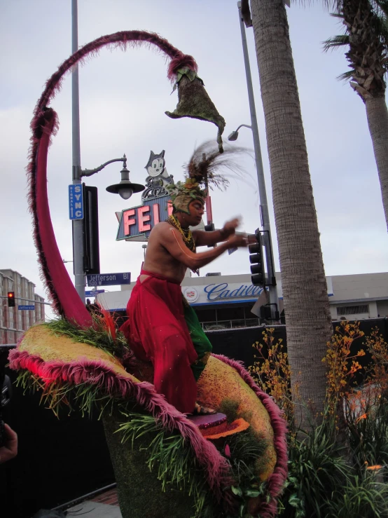 a man with long hair and a dress performs in the parade