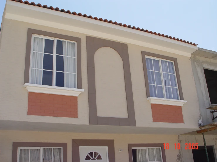 a tan house with three windows, and a white door