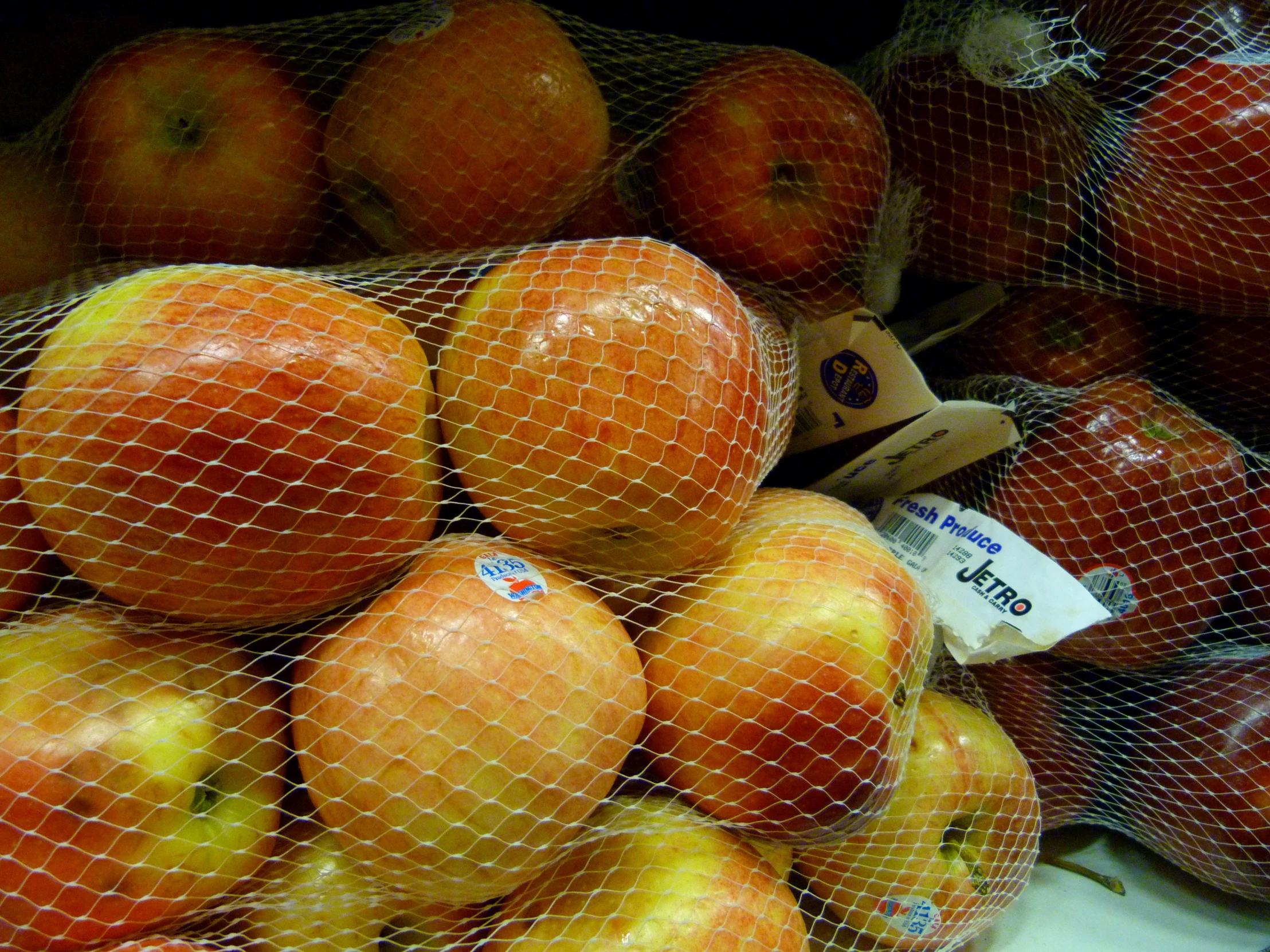 an assortment of fresh produce sits in a mesh bin