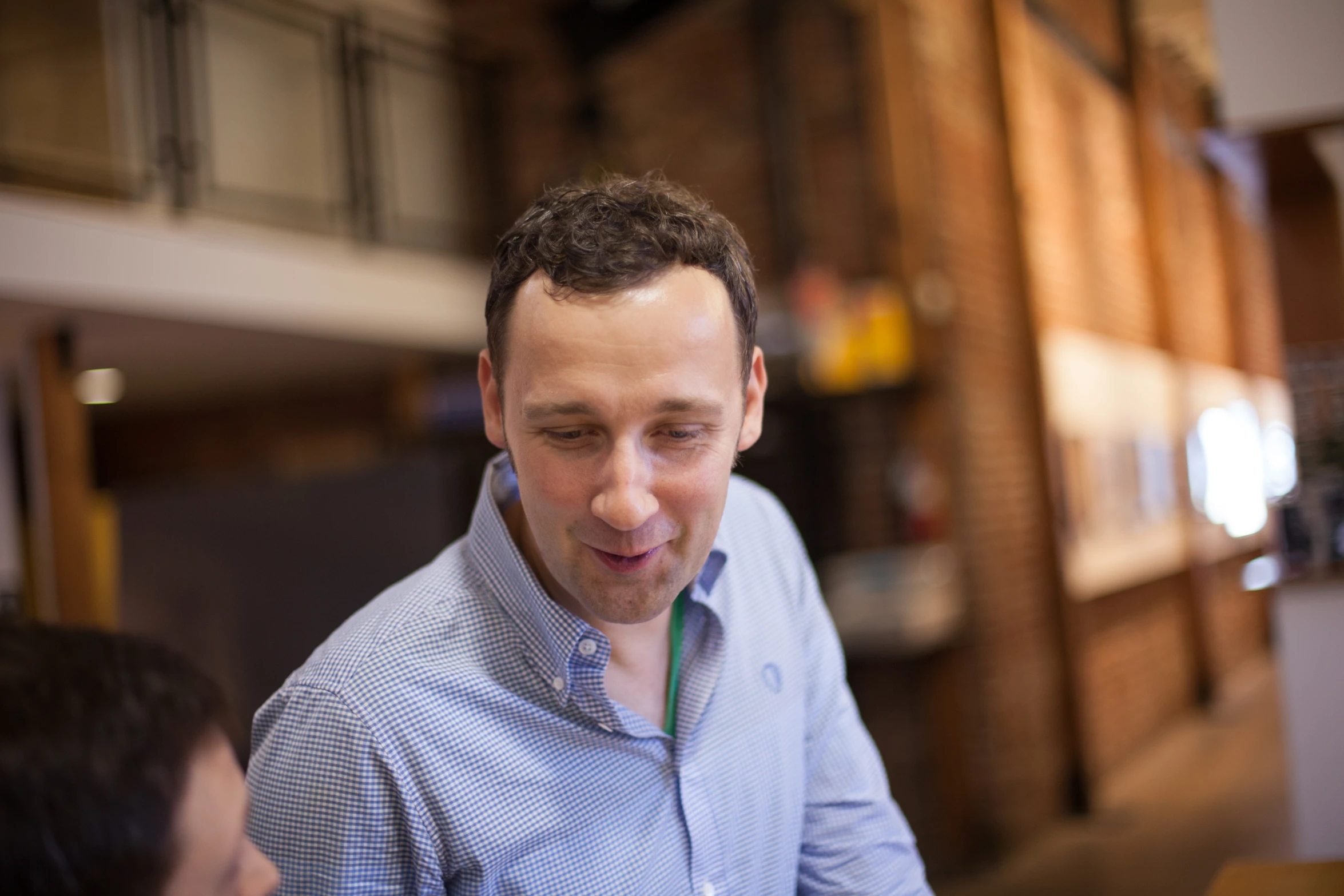 a man wearing a blue shirt sits down looking at his cell phone