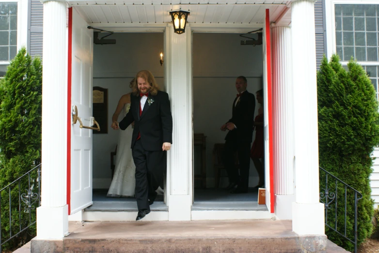 a woman is walking out of a red and white house