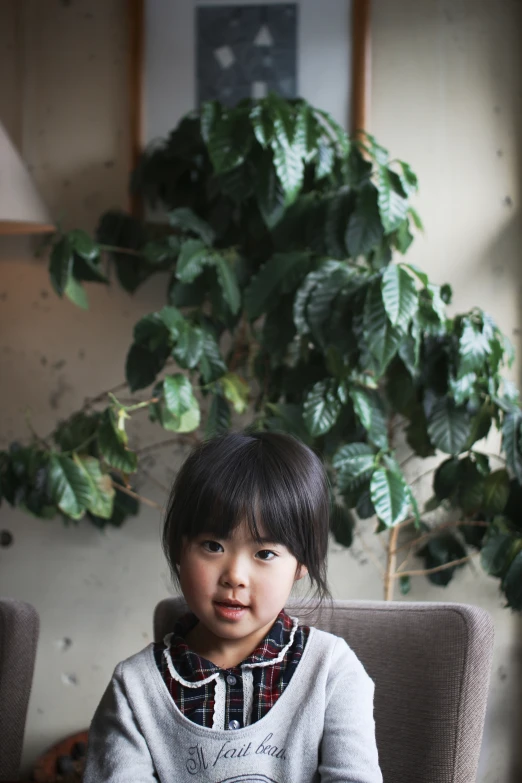 a little girl sitting in front of some plants