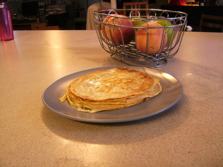 the plate holds a piece of cheese panini and apples in a wire basket