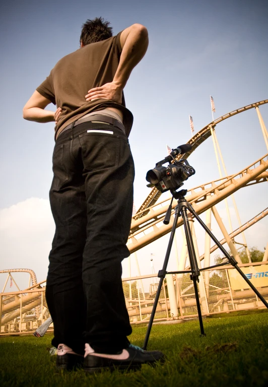 a man holding a camera with his hands near the camera and telescope on a tripod