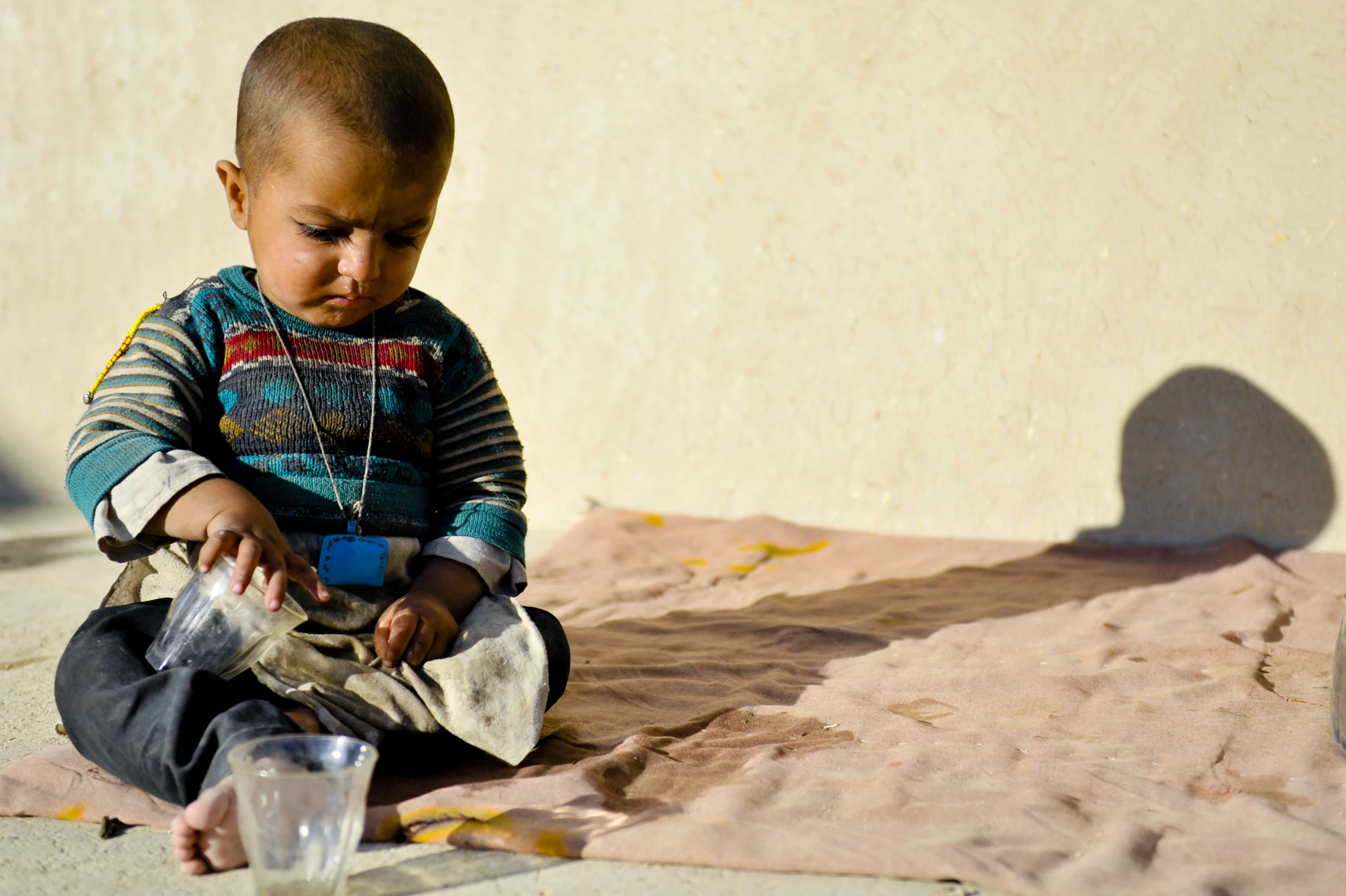 a small boy with an open umbrella sitting on the ground