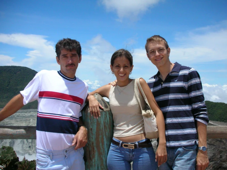 three people standing next to each other near a cliff