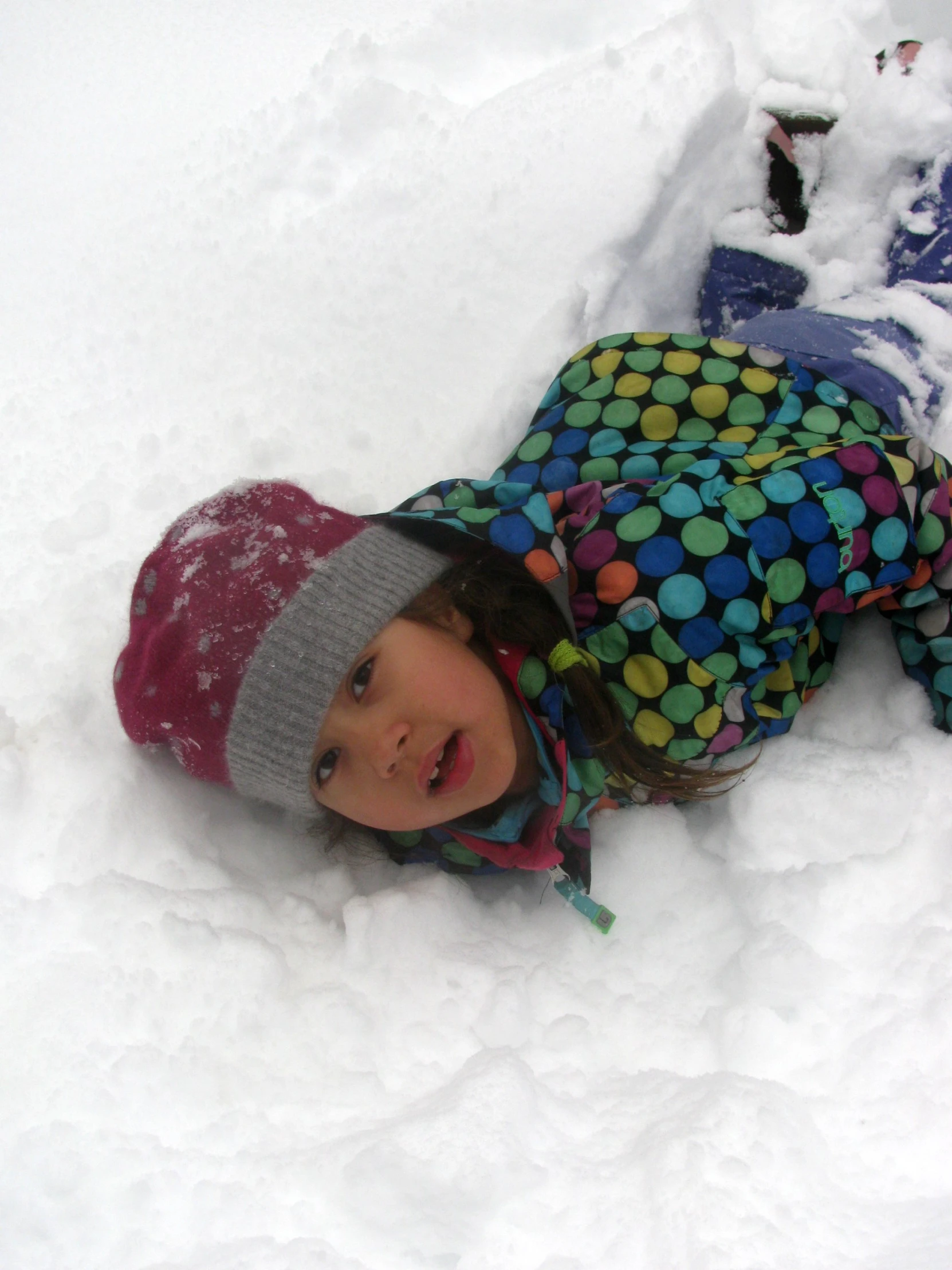 a small child laying in the snow near a fire hydrant