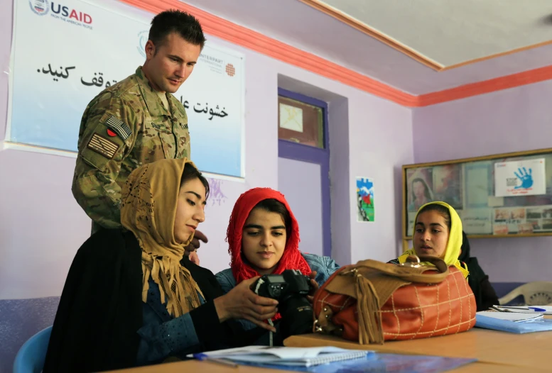 two women and one man in army clothes are talking to two men