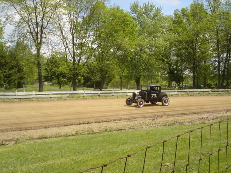 a car driving down a dirt road on a sunny day