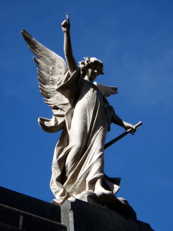 the angel statue is holding an arrow and wearing a long skirt