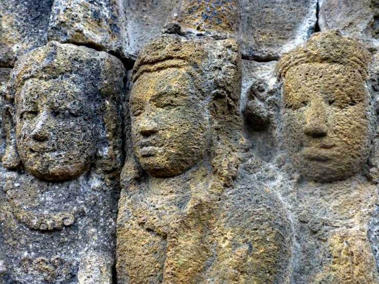 carved faces are on the rocks by the water