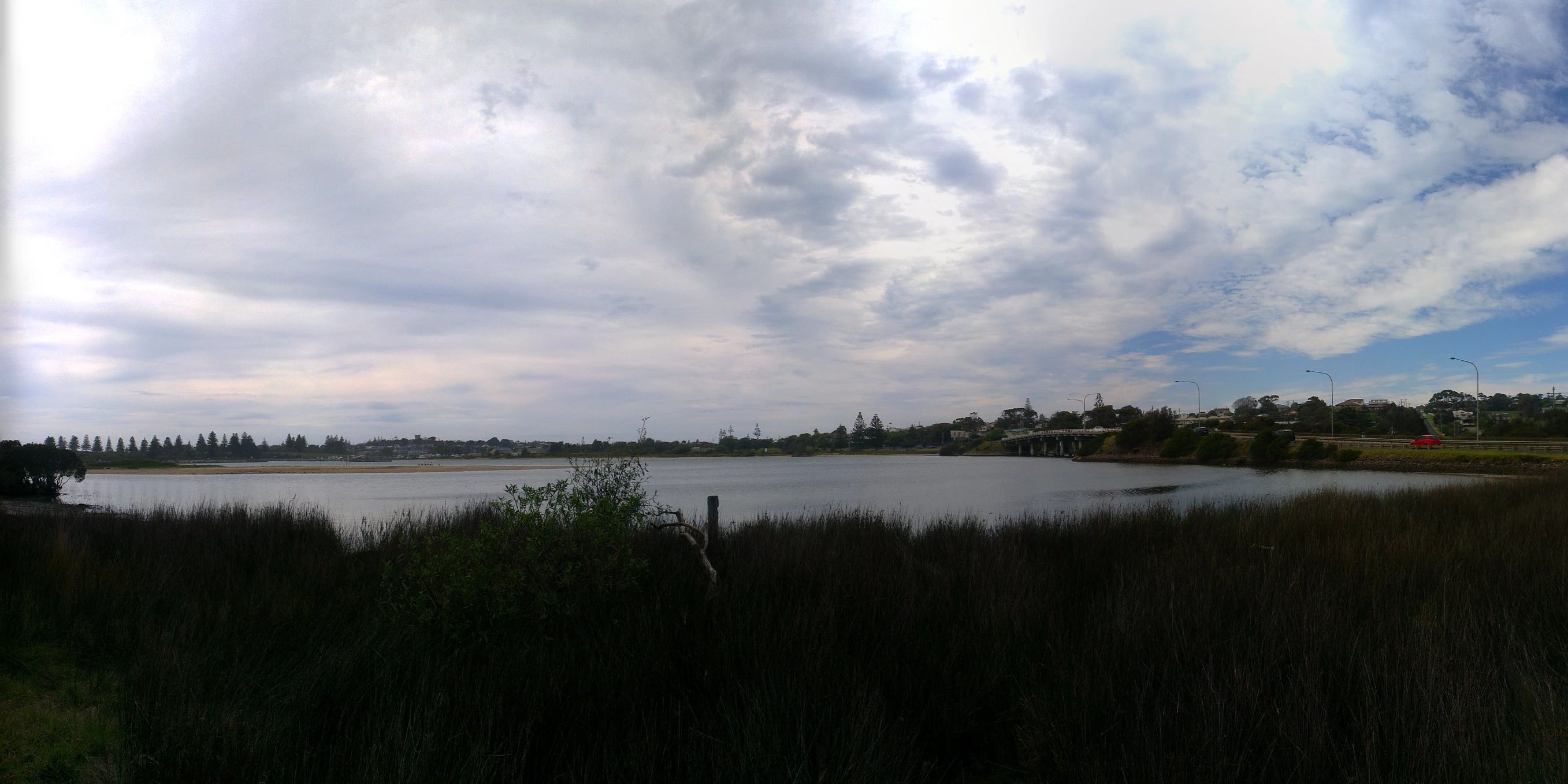 a large body of water with a cloudy sky above it