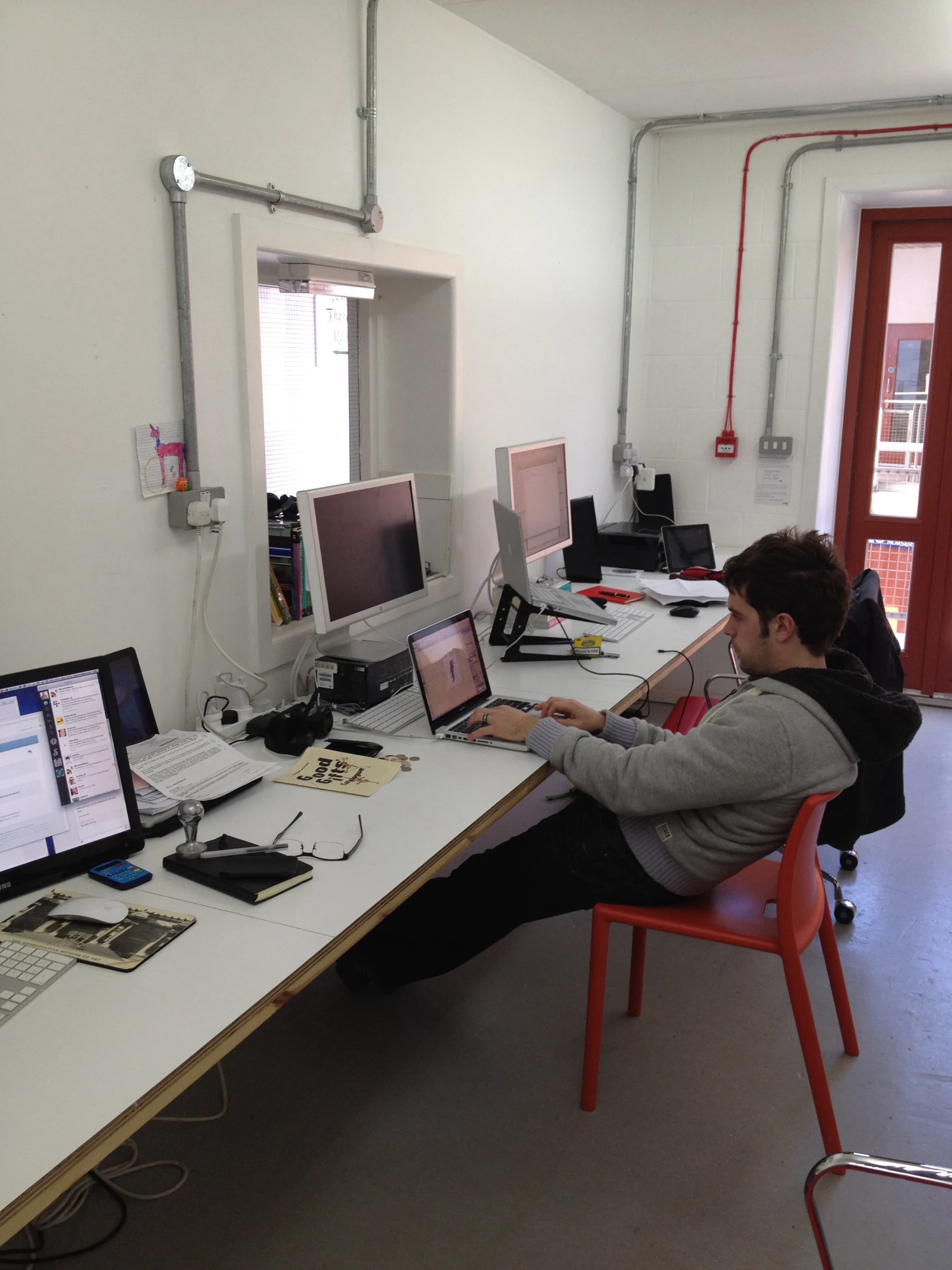 a man sits in an office chair near two computers on a desk