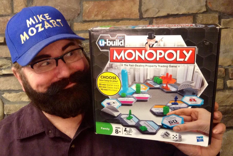a man wearing a hat holding a monopoly board game
