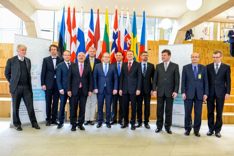 several business men stand together in front of a group of flags