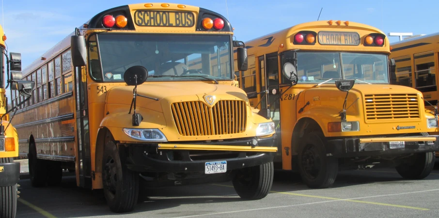 three school buses sitting parked on the side of a street