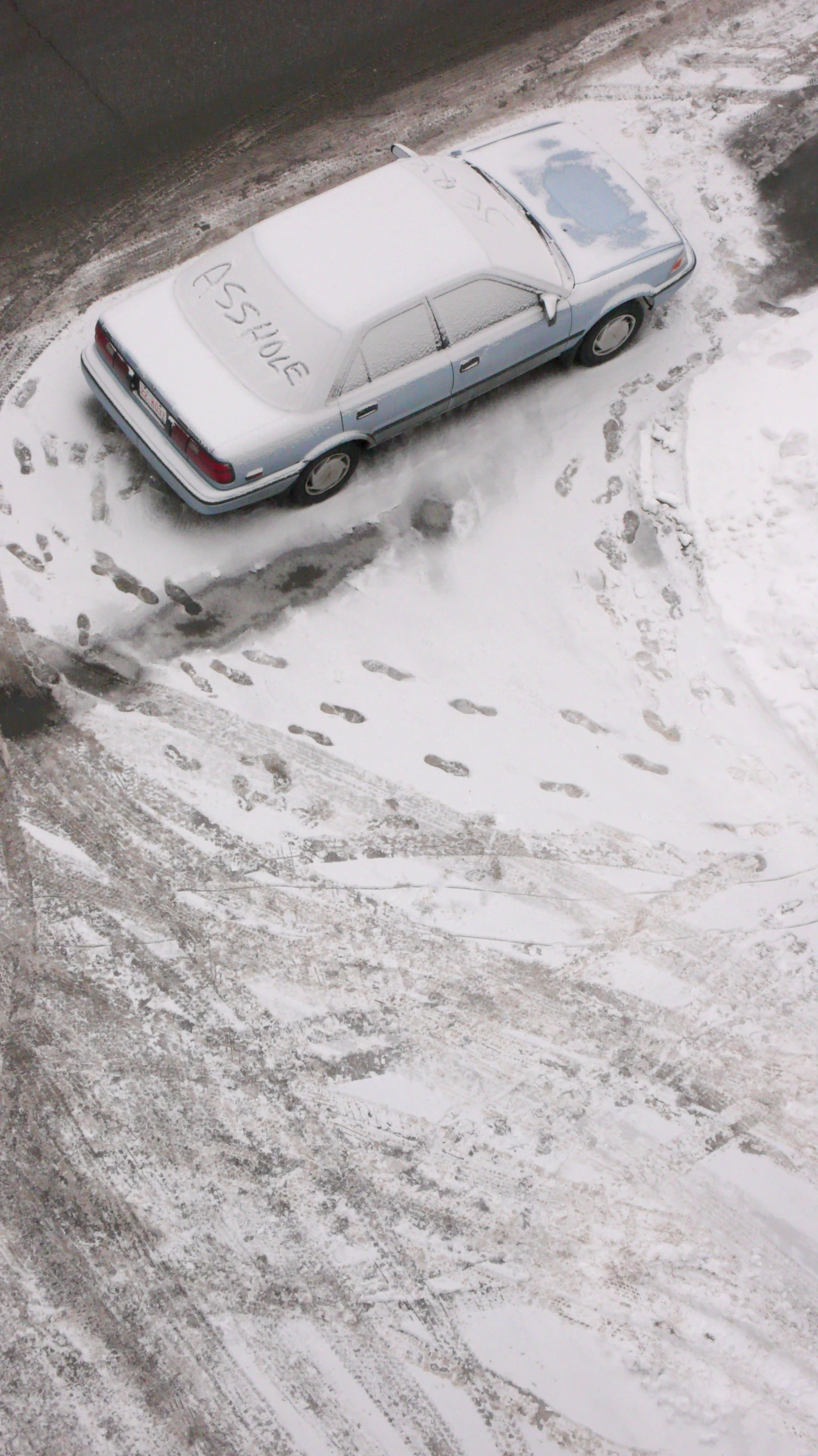 a snow covered car on a road next to trees