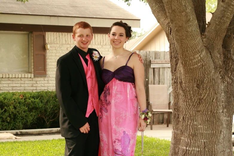 a couple poses in front of a tree at their wedding