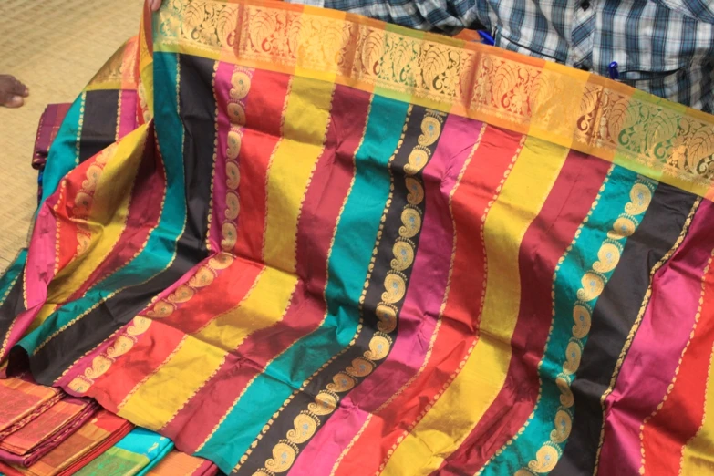 man in blue shirt and black shirt holding striped piece of cloth