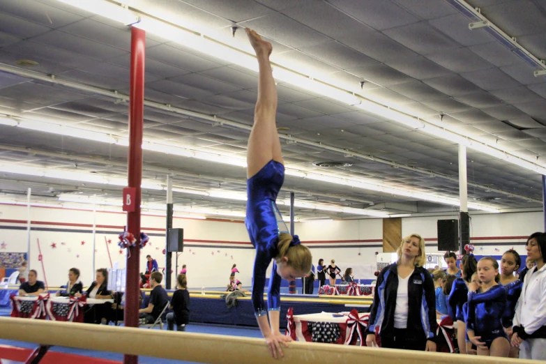 woman is standing on the bar in a gymnastics practice