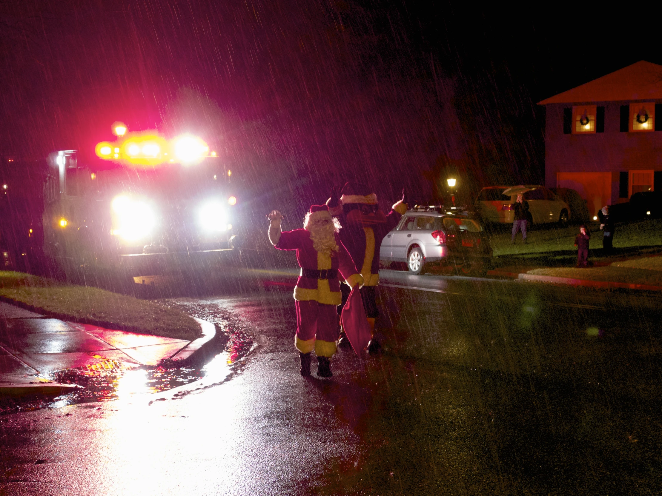 fire fighters at night in the rain next to a car