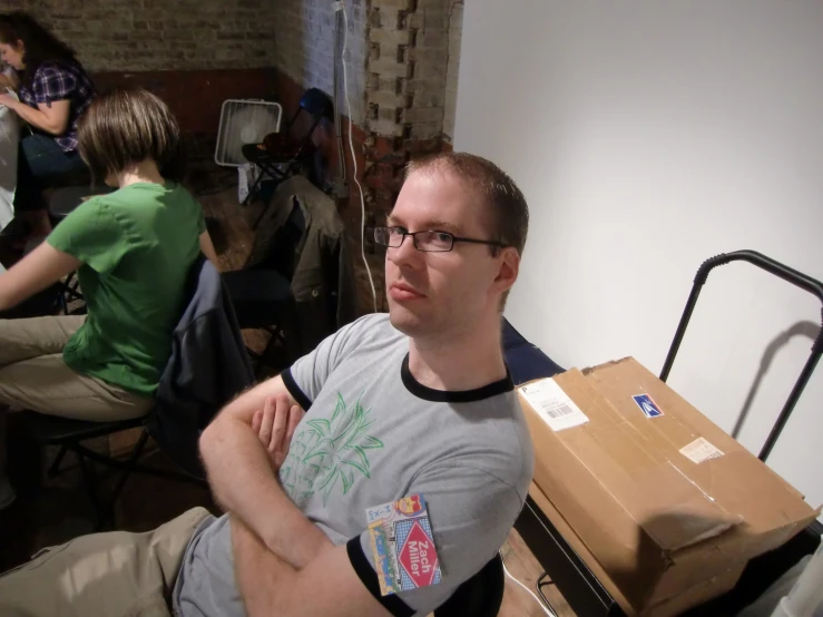 a man wearing glasses sitting in front of a table with boxes on it