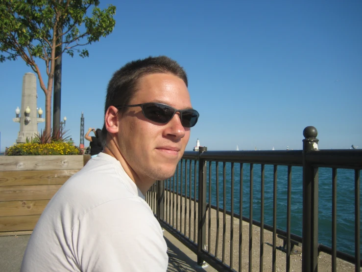 a man wearing sunglasses is sitting by the water