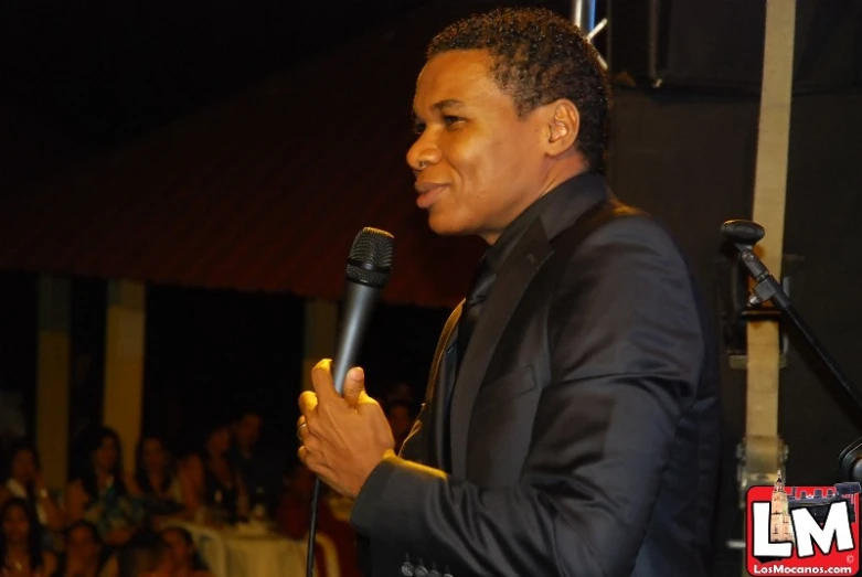 a man in suit speaking into a microphone