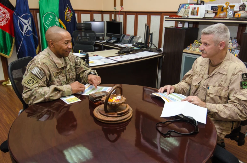 two men in uniforms are talking at a table