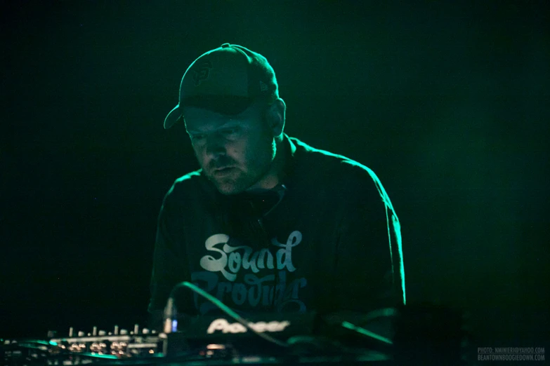 a man plays keyboards in front of a green light