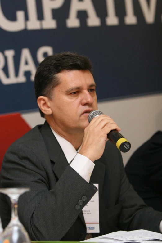 a man holding a microphone with both hands at a press conference