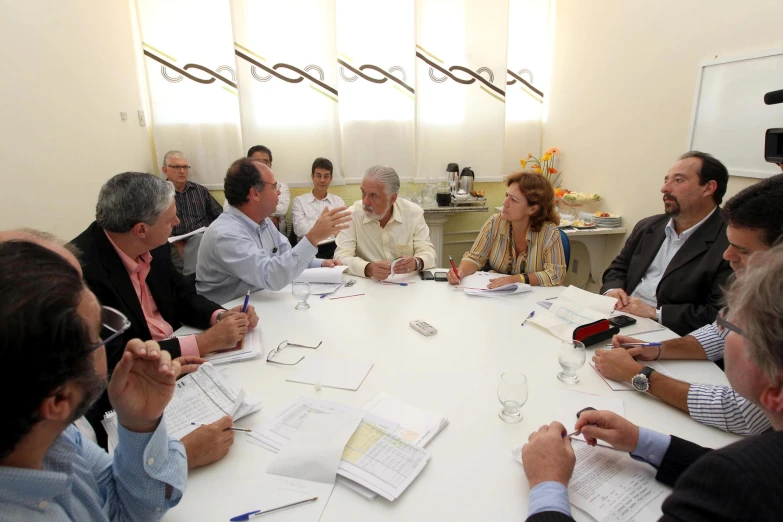 people are gathered around a table looking at paper